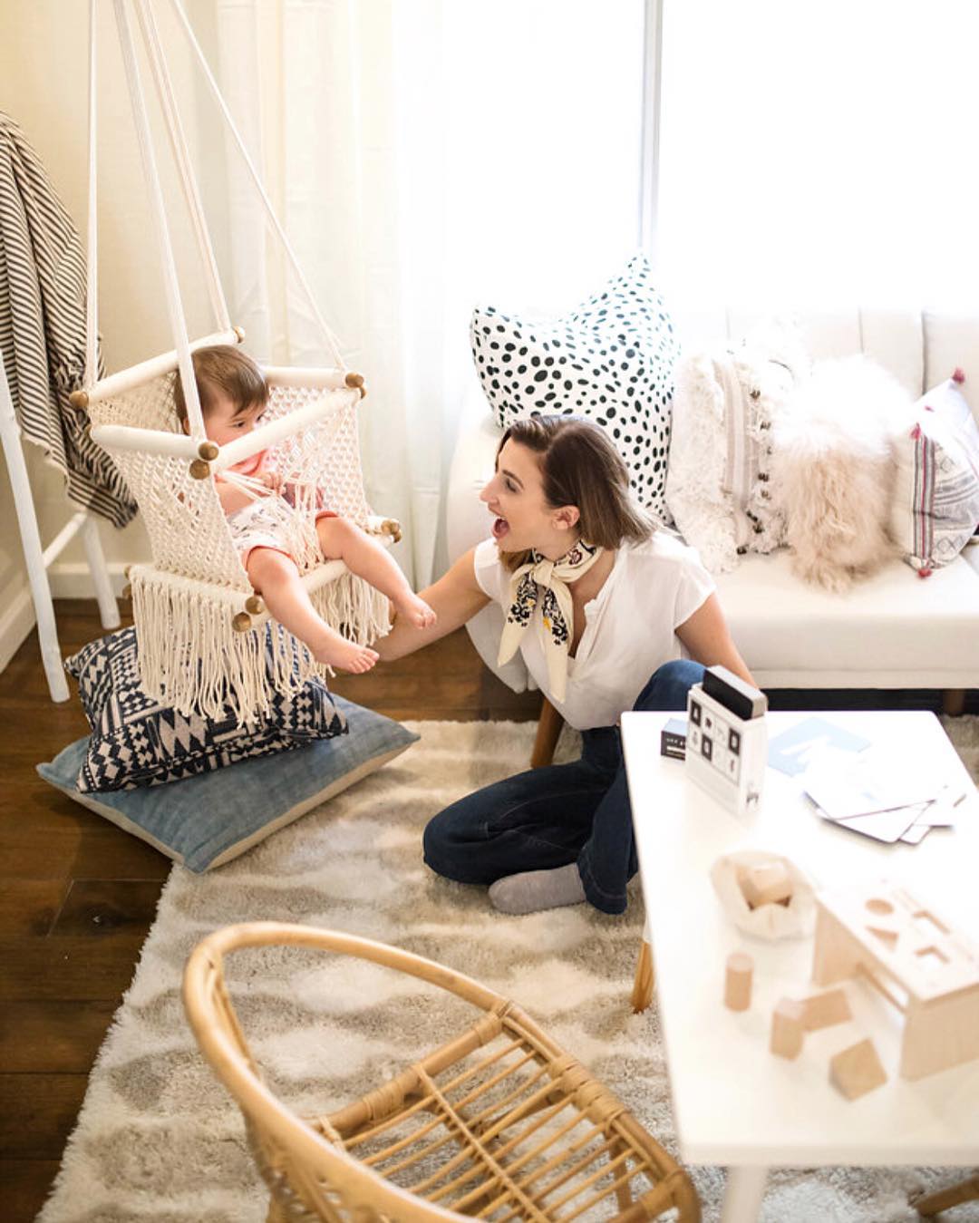 mother watching her baby on a swing in a nursery room