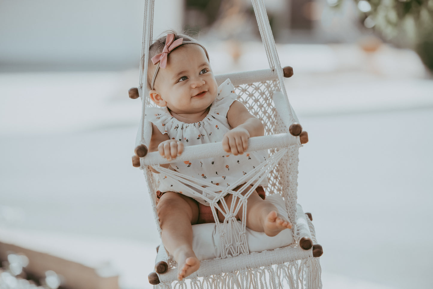 close-up of a baby sitting on a macrame swing chair