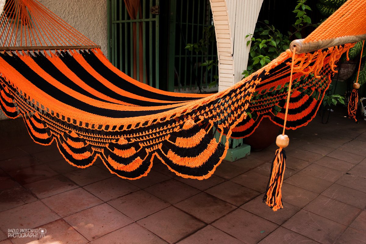 Orange and black cotton hammock hanging in the front porch