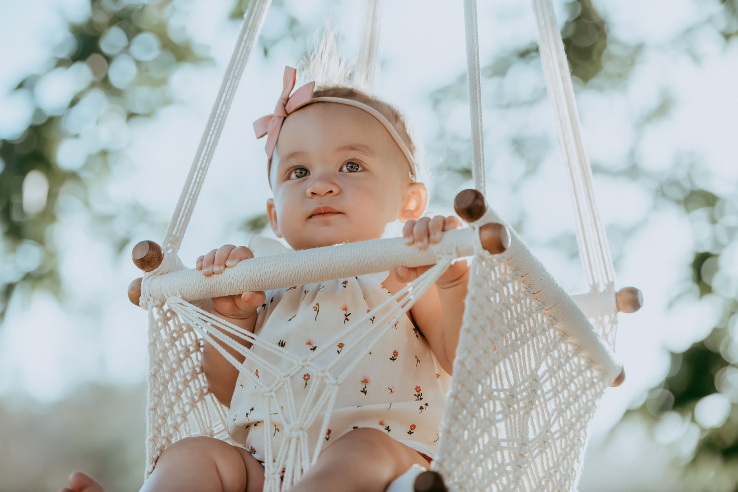baby on a white swing chair in the backyard