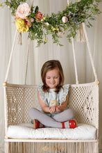 kid girl sitting on a swing chair watching a chick in her hands