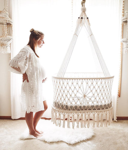 hanging cradle (hanging bassinet) in a babyroom with a pregnant mother near by