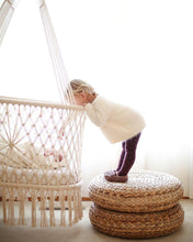 hanging cradle (hanging bassinet) in a babyroom with a kid watching the baby inside the cradle