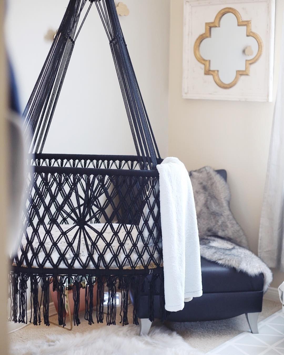 black color hanging bassinet next to a armchair