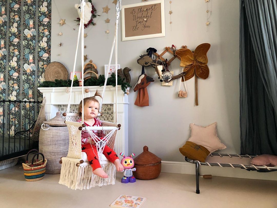 baby sitting on a swing chair in the bedroom