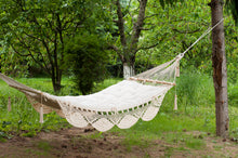 hammock with wool cushion. Green backyard with grass and pines