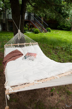 hammock with wool cushion. Green backyard with grass and pines
