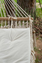 hammock with wool cushion (detailed picture). Green backyard with grass and pines