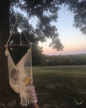 hammock chair hanging under a big tree during the sunset with a kid sitting and reading