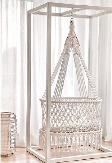 macrame bassinet hanging from a wooden structure